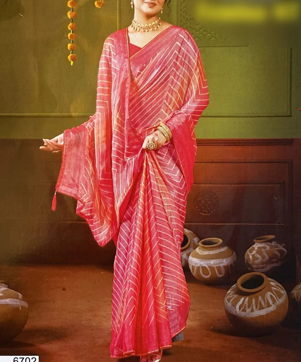 Woman in a red saree with white patterns standing in a room with decorative pots.