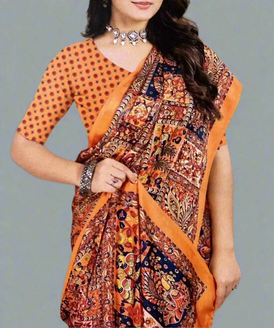 Woman wearing a traditional orange and patterned saree against a grey background