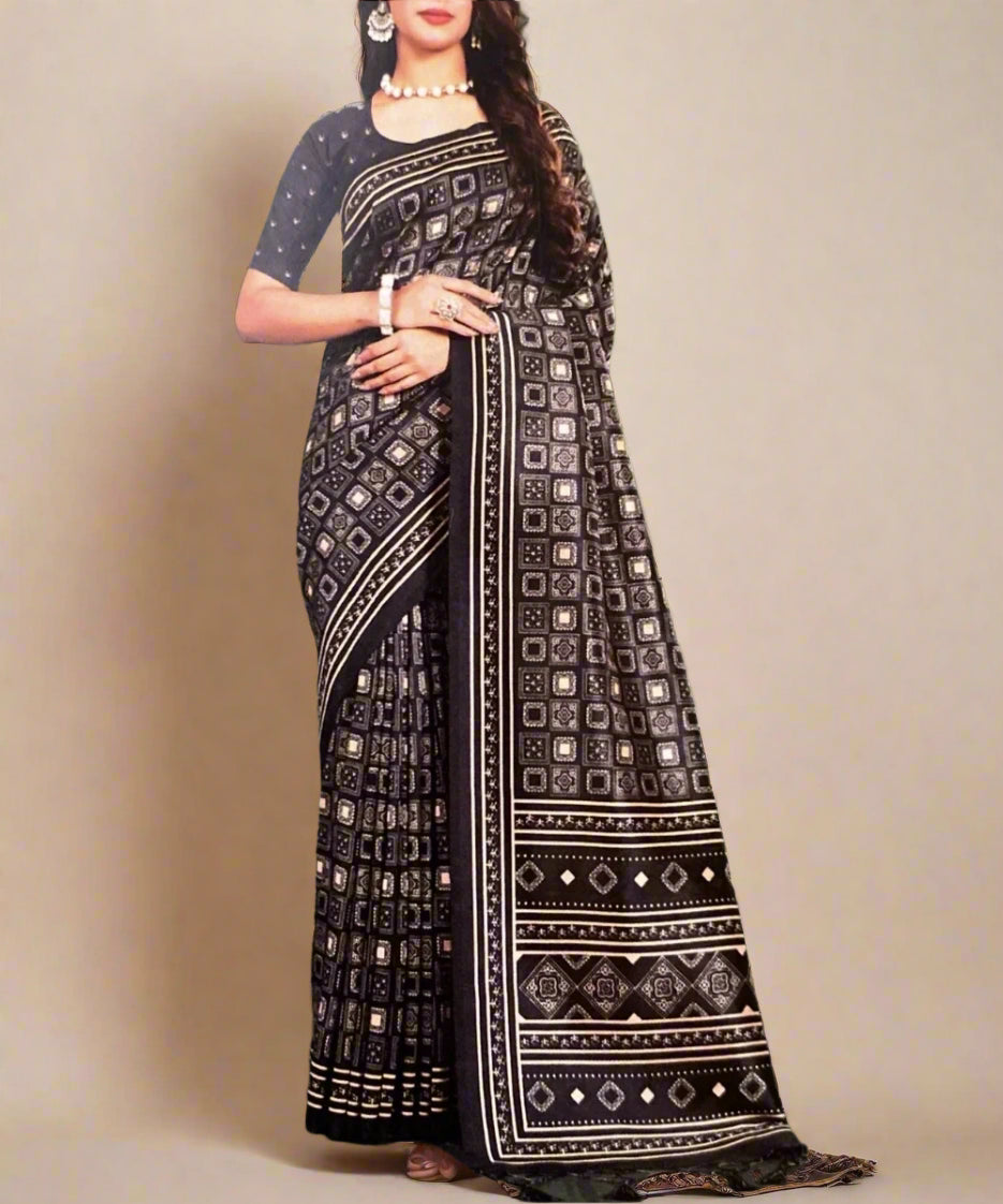 Woman wearing a black and gold patterned saree against a grey background