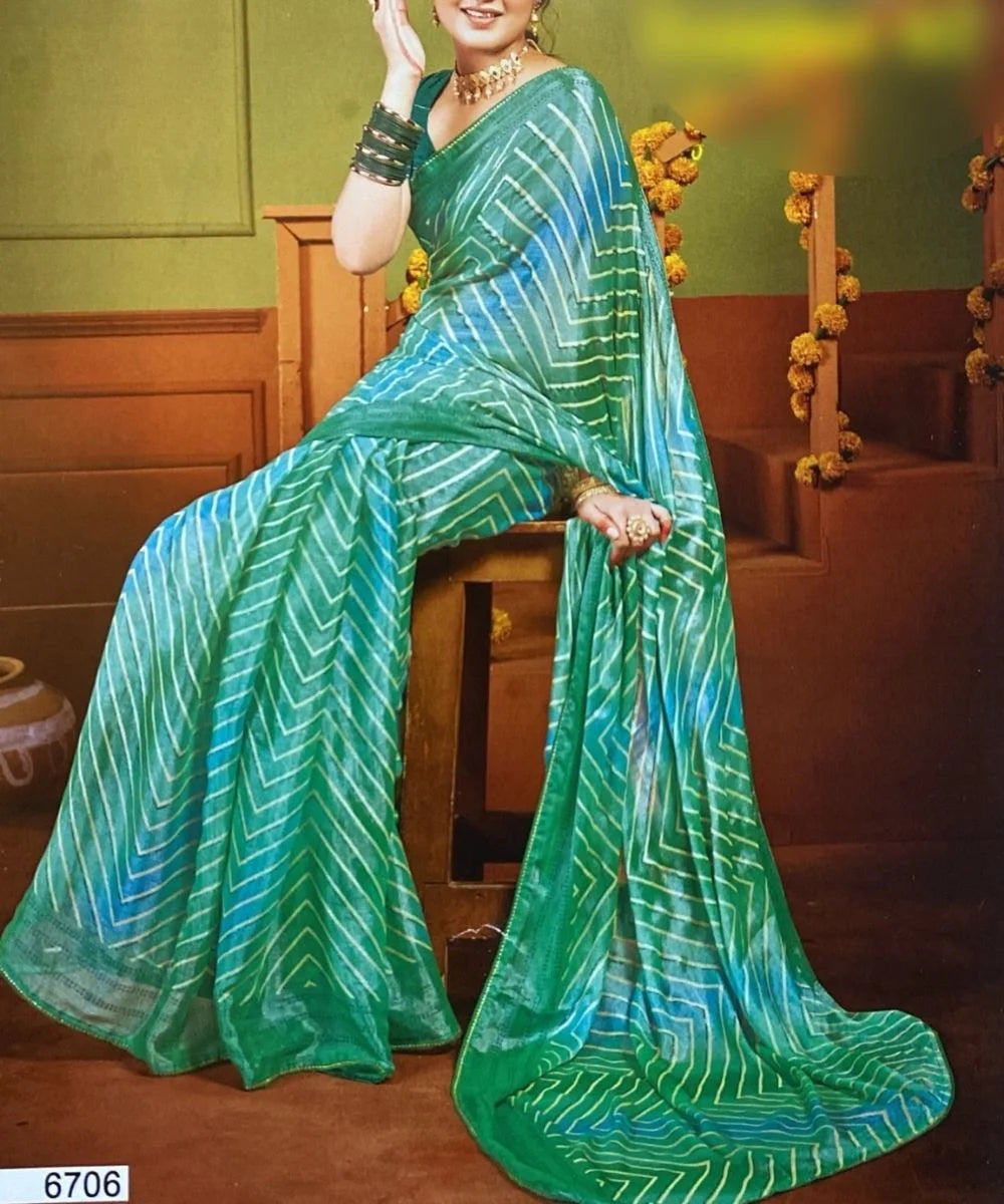 Woman wearing a green saree with white patterns sitting on a brown chair.