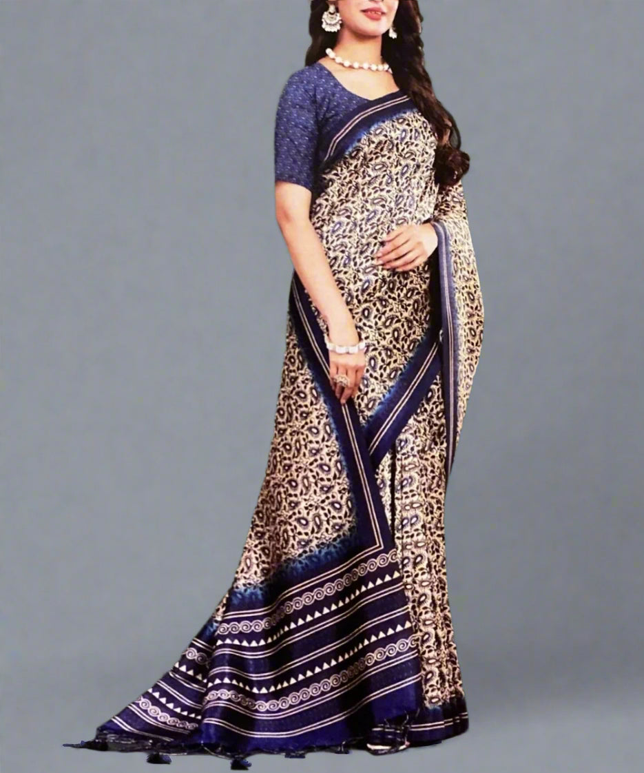 Woman wearing a paisley print saree with blue border against a gray background