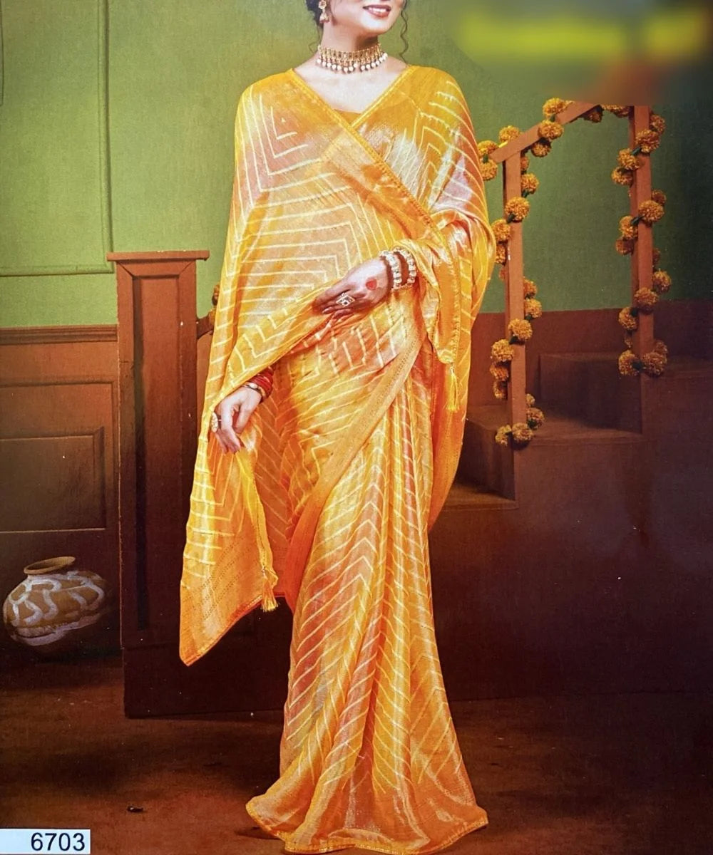 Woman wearing a bright yellow saree with a green wall and wooden furniture in the background.
