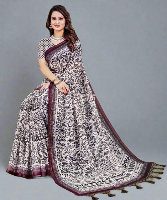 Woman wearing a off white patterned saree with a maroon border .