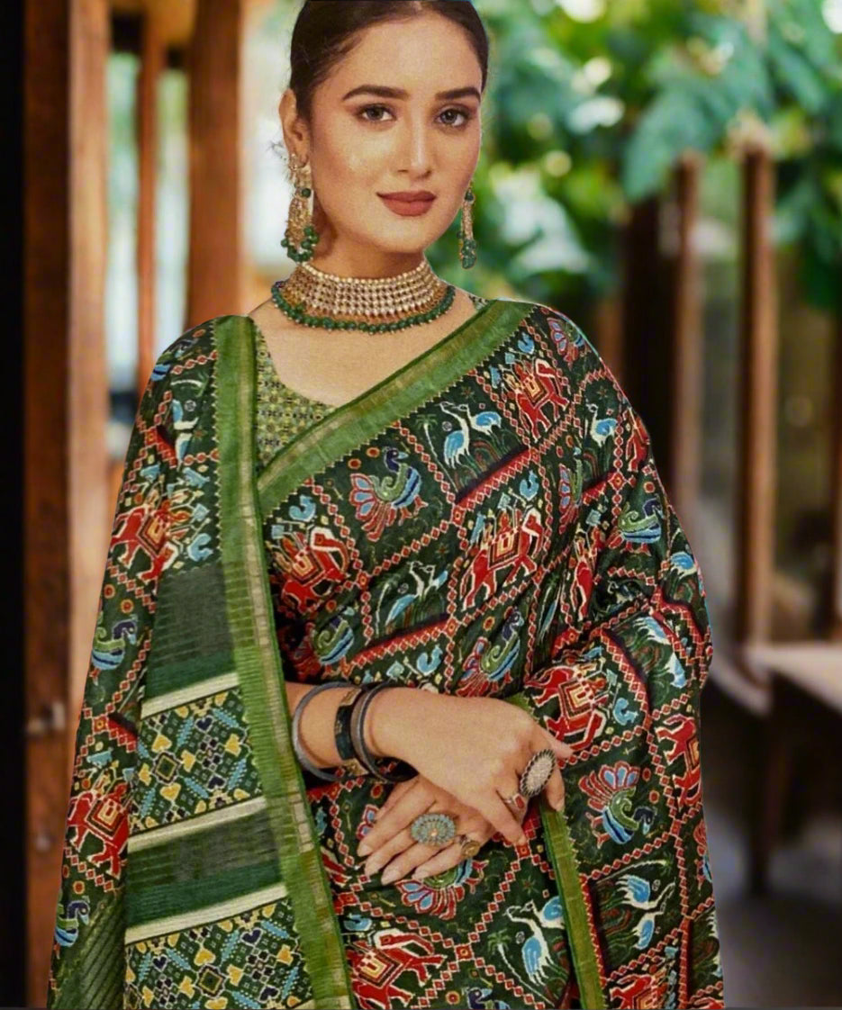 Woman wearing a traditional printed saree with a green border against a decorative wall.