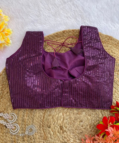 Back design of Wine colored sequin blouse, displayed on a beige background with flowers and jewelry in the periphery.