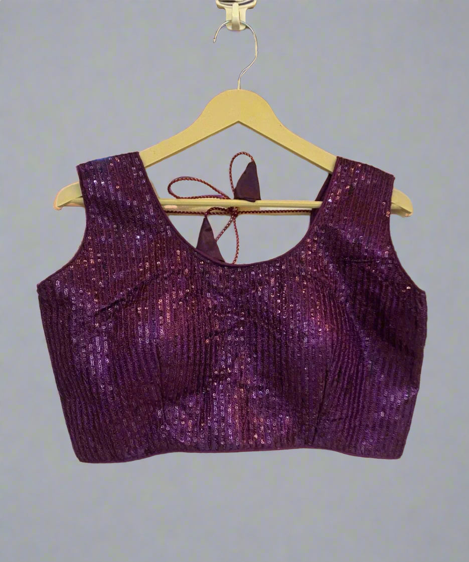 Wine colored sequin blouse with a round neck and sleeveless design, displayed on a hanger.