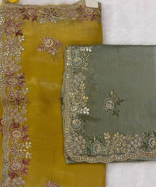 Two traditional sarees displayed, one with a mustard color and the other with a mehendi green color, both with detailed embroidery along the scalloped borders.