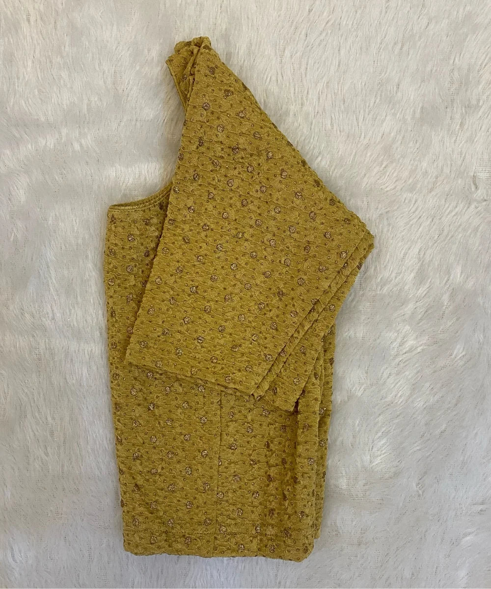 Folded mustard yellow fabric with small patterns on a white textured background
