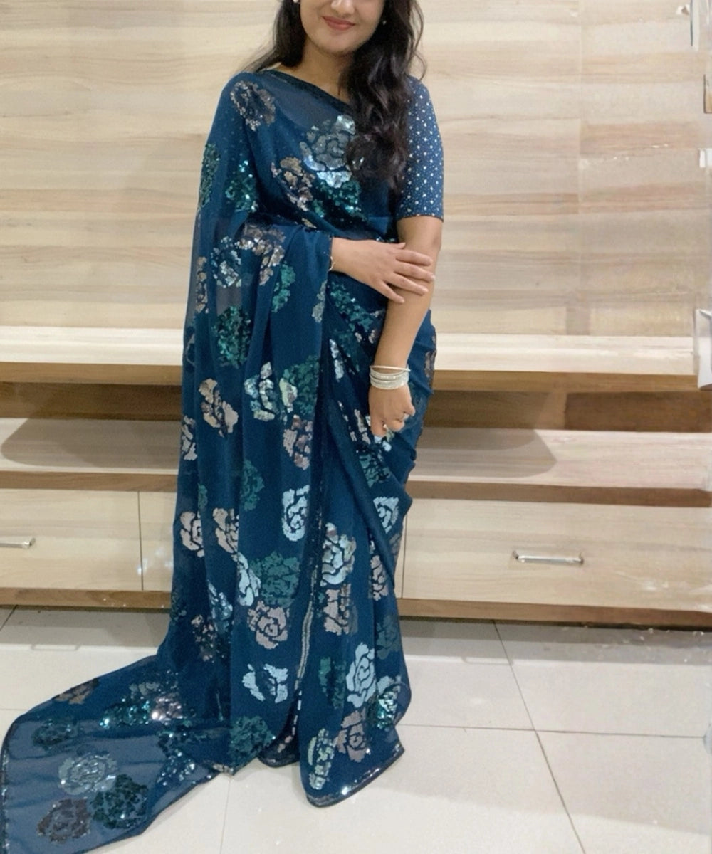 Woman wearing a blue saree with floral patterns.