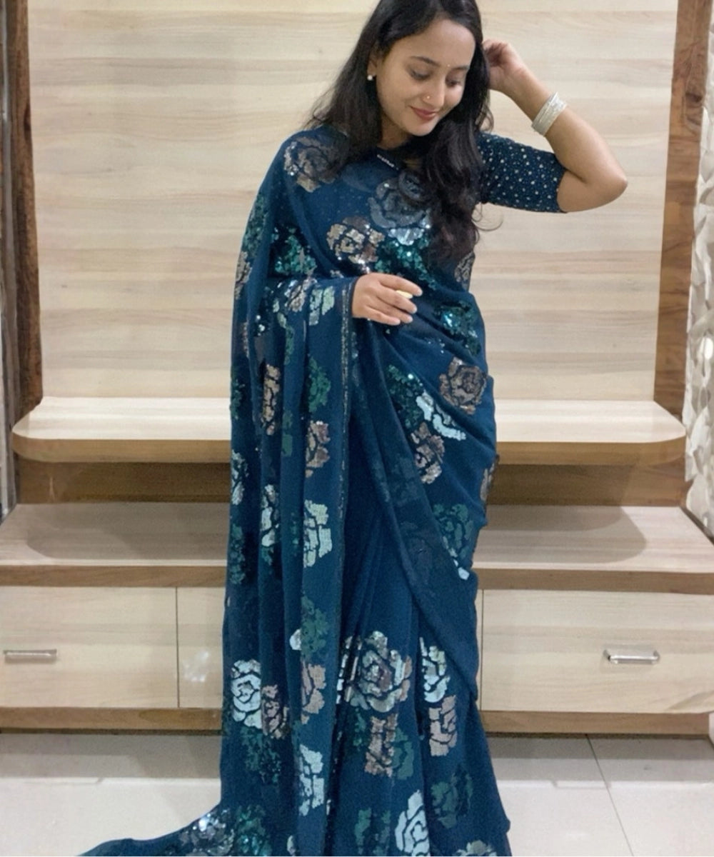 Woman wearing a blue floral saree in an indoor setting