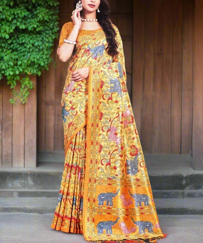 Woman wearing a colorful yellow saree with elephant patterns against a dark background