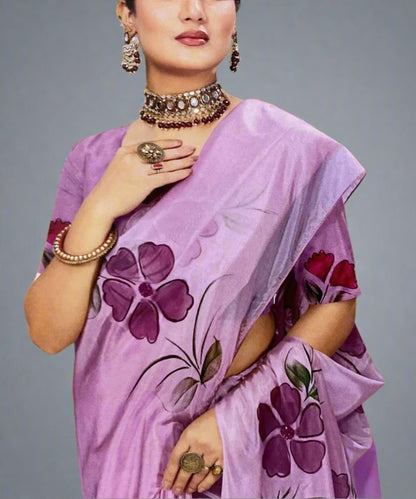 Woman wearing a purple hand-painted saree with floral patterns on a grey background