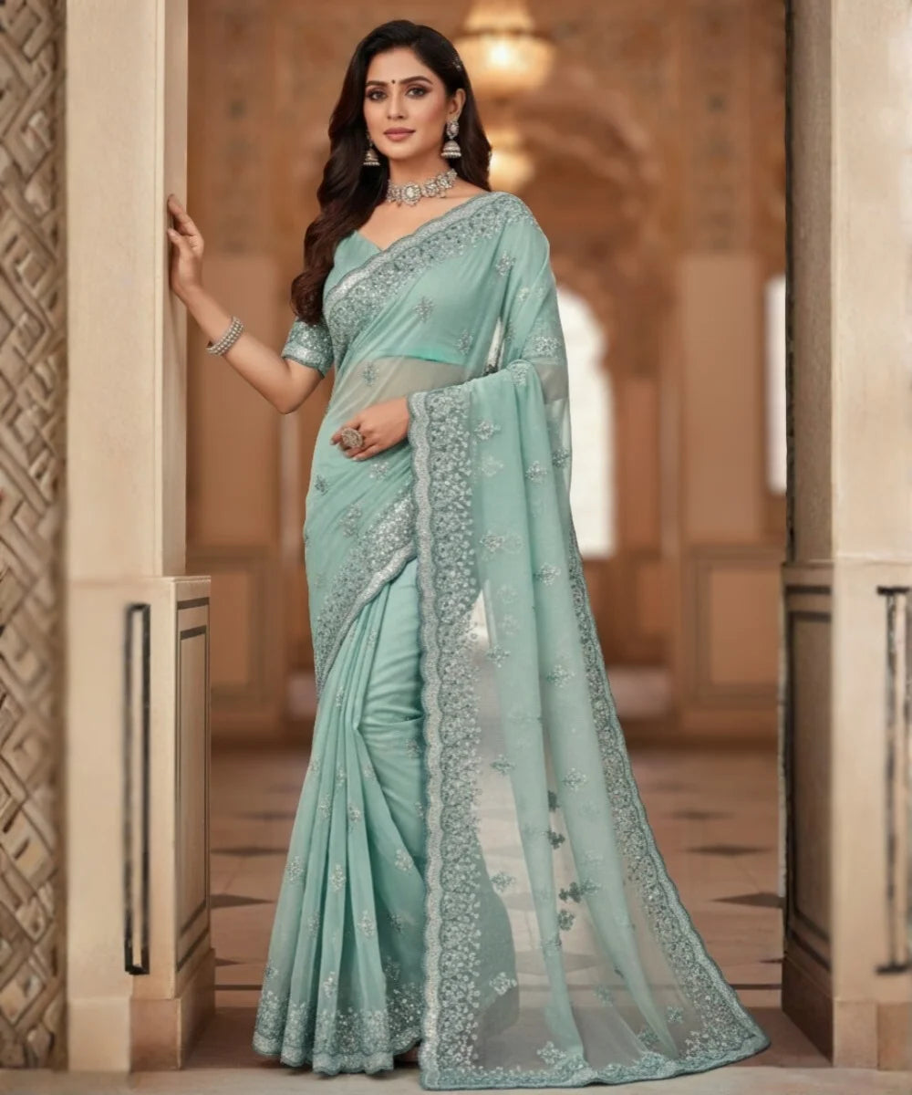 Woman wearing a light blue net saree with embroidery in an indoor setting.