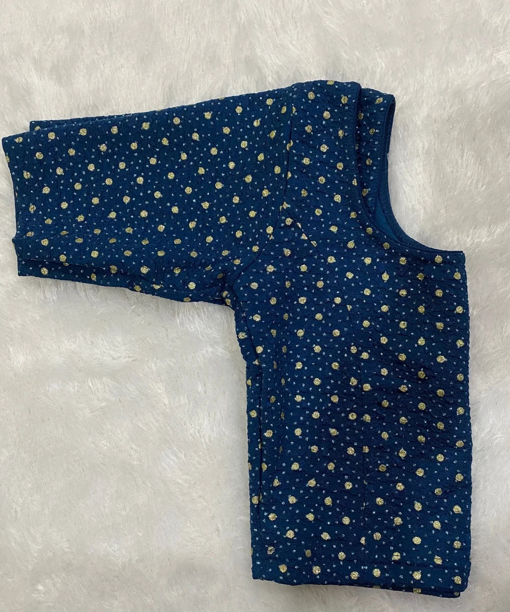 Folded Blue cotton stretchable blouse with gold polka dots on a white background.