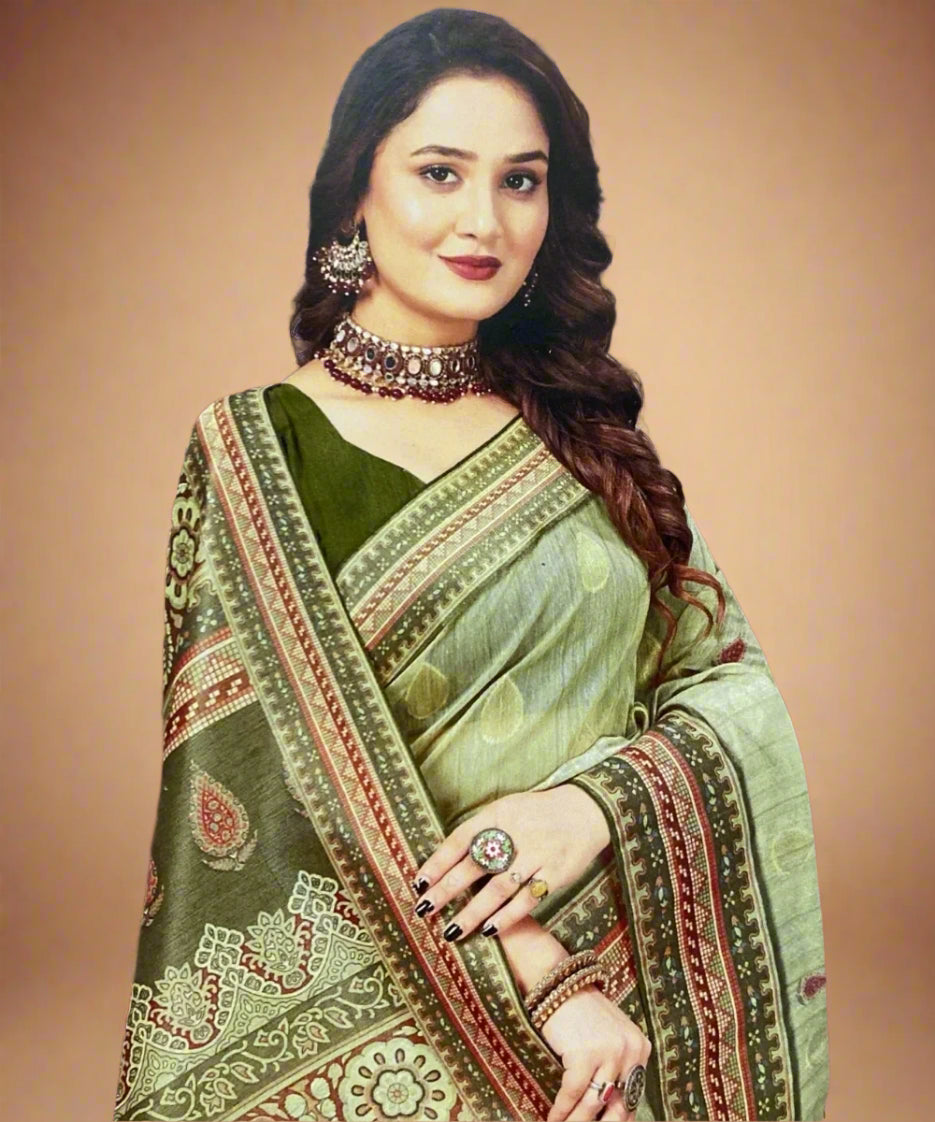 Woman wearing a green saree with intricate patterns and jewelry against a brown background