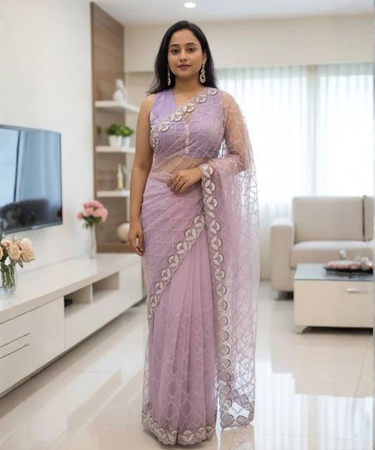Woman in a lavender saree with silver patterns standing in a modern living room.