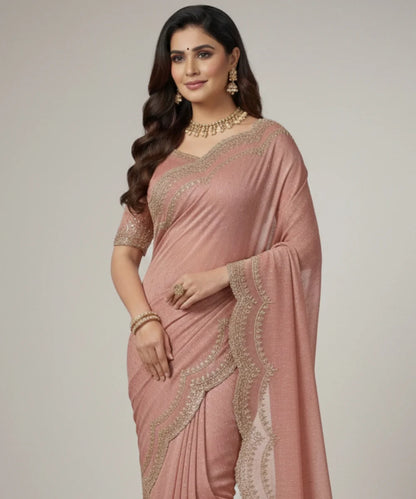Woman wearing a pink saree with stone embroidery on a plain background