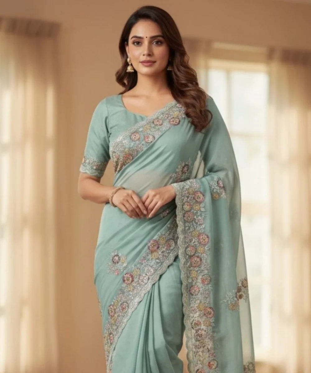 Woman wearing a light blue saree with floral patterns indoors