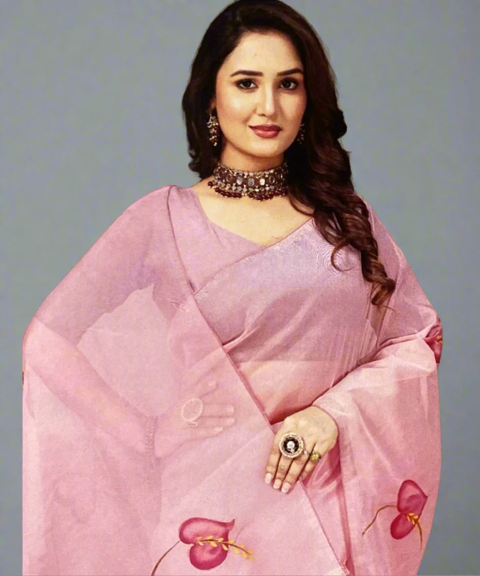 Woman wearing a pink hand-painted organza saree with floral patterns on a plain background