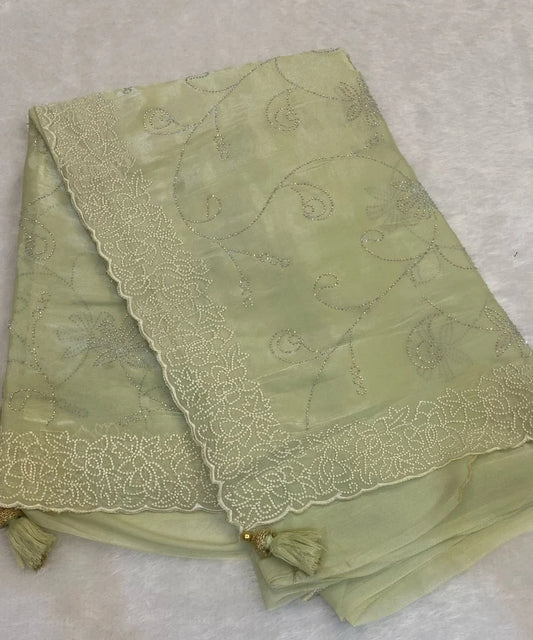 A green saree with floral embroidery and tassel details, laid flat.
